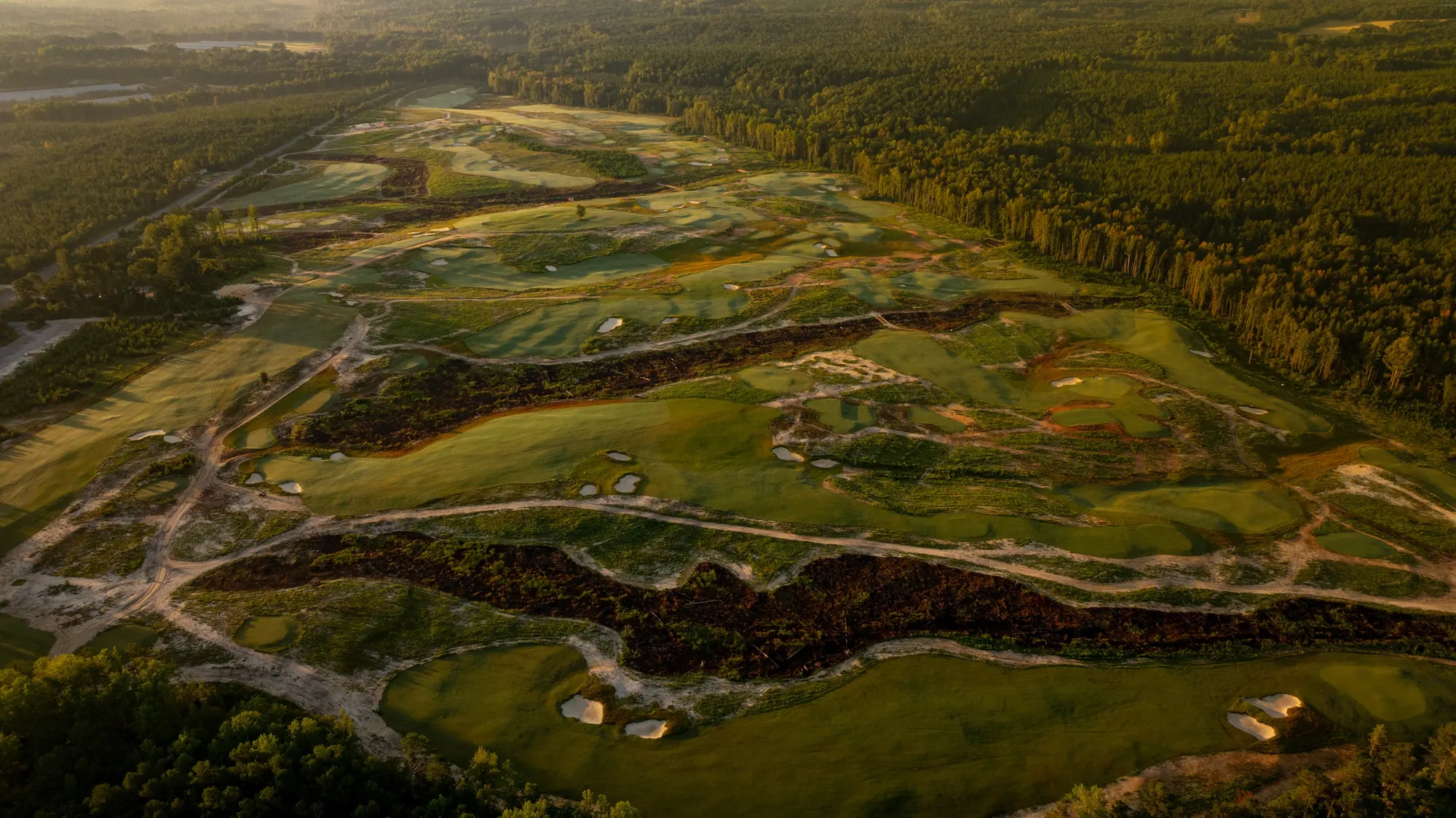 Candyroot Lodge from the air at dawn: sandy fairways cut through the pines